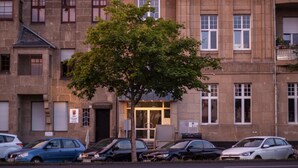 Un edificio de varios pisos con un árbol en primer plano.