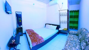 A bedroom with a bed, a sofa, a TV, a mirror, and an air conditioning unit. - Hotel Citizen (Khulna)