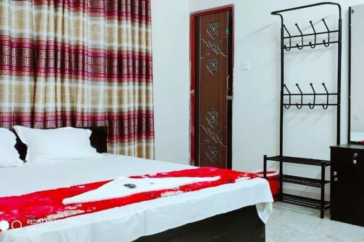 A hotel room with a bed, a desk, a chair, a wardrobe, and a hanging clothes rack.
