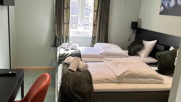 A hotel room with two beds, a desk, and a TV.