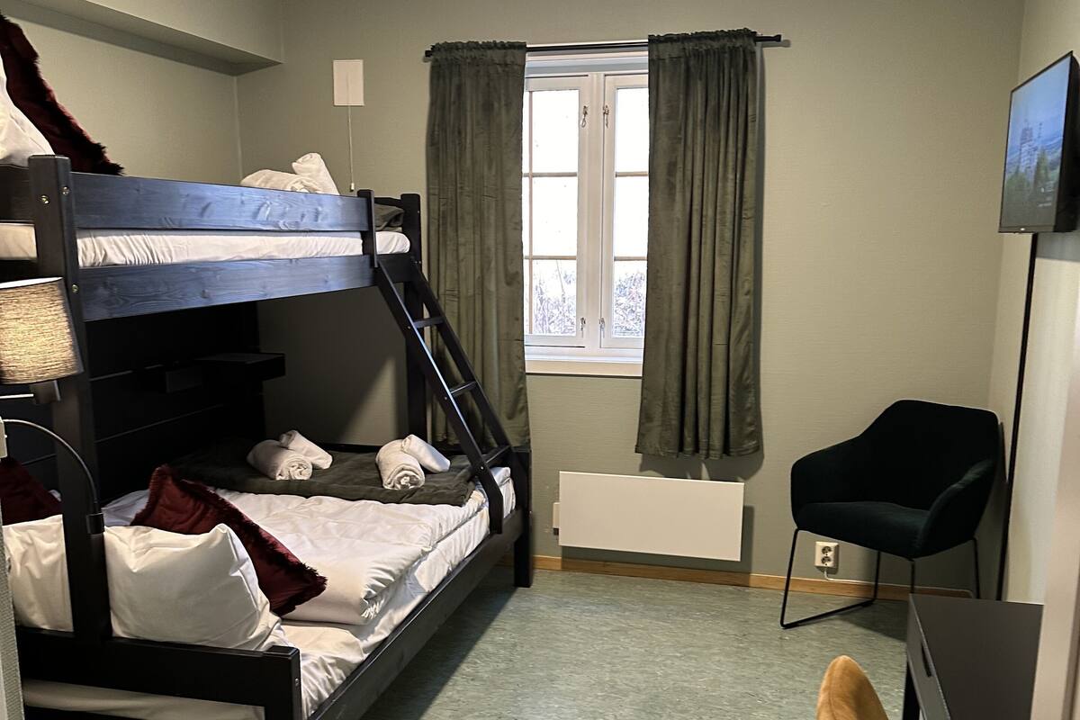 A compact room with bunk beds, a desk, a chair, and a television.