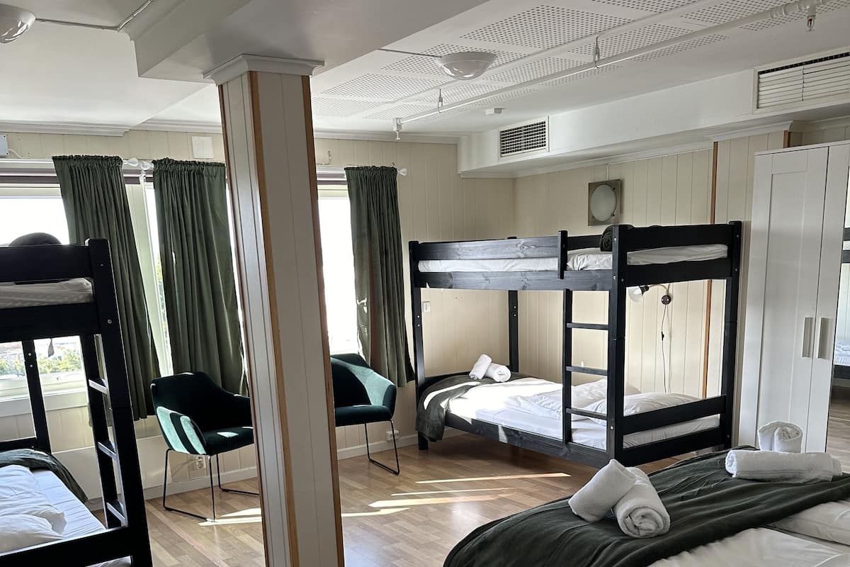 A dormitory room with bunk beds, a desk, and a chair.