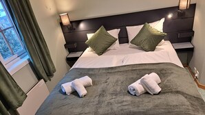 A neatly made bed with a dark green blanket, two rolled towels, and two green pillows. - Tune Hotell Sarpsborg (Sarpsborg)