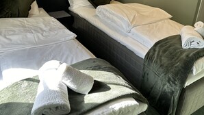 A hotel room with two beds, a nightstand, a wall-mounted lamp, and a painting. - Tune Hotell Sarpsborg (Sarpsborg)