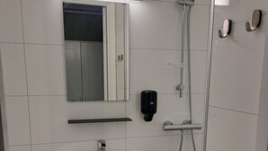 A bathroom with a white sink, mirror, and shower. - Tune Hotell Sarpsborg (Sarpsborg)