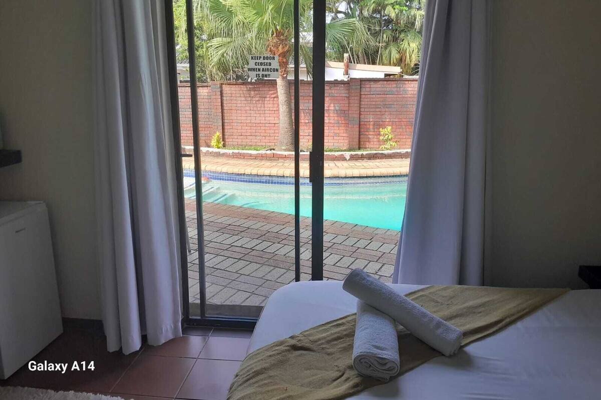 A bedroom with a view of a swimming pool, a Galaxy A14 laptop, and a towel on the bed.