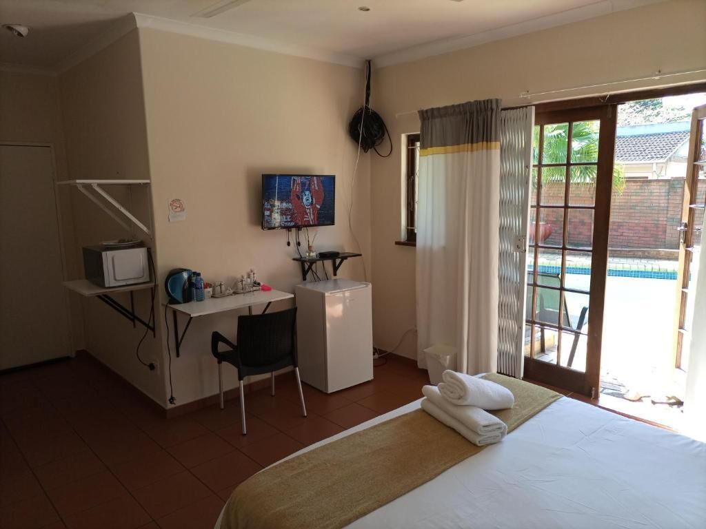 A hotel room with a bed, a desk with a computer, a TV, and a view of a swimming pool.