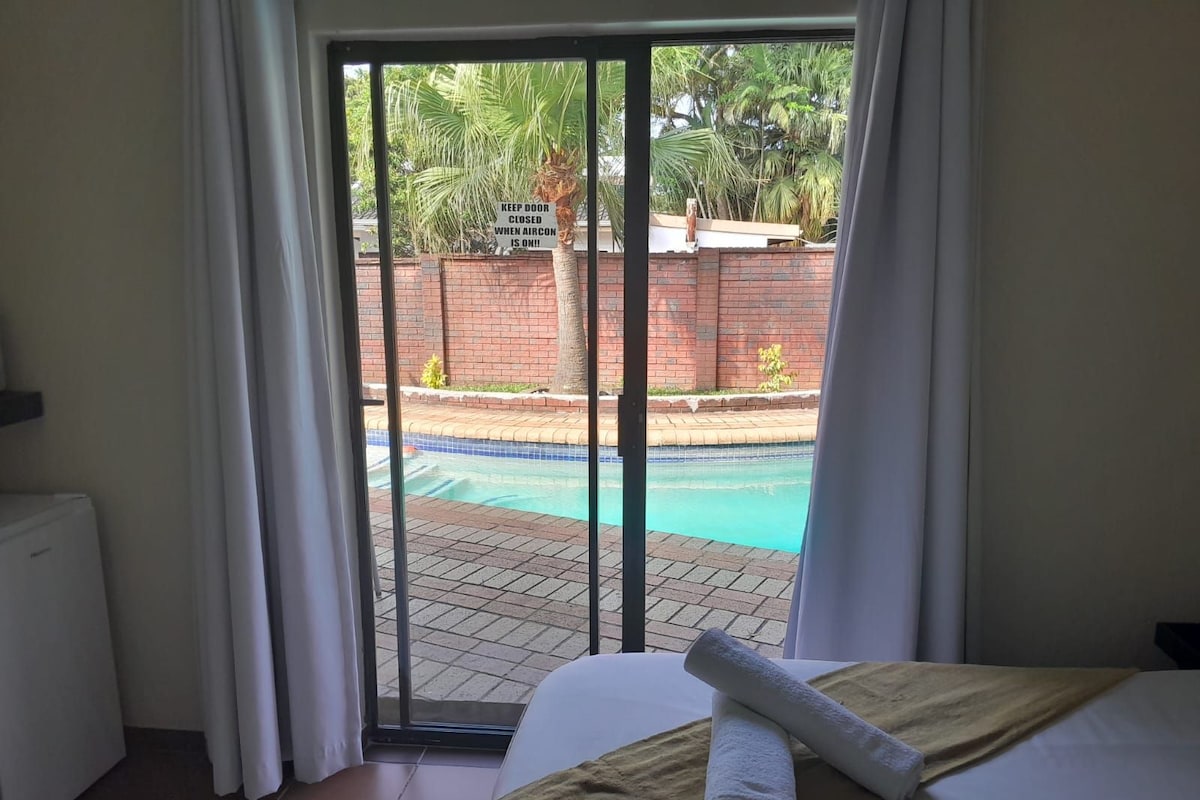 A bedroom with a view of a swimming pool, a Galaxy A14 laptop, and a towel on the bed.