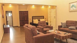 A spacious living room with a large sofa set, a coffee table, and a bed with a headboard. - Guest House Quatre Saisons (Cotonou)