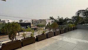 A spacious balcony with tiled flooring, wooden planters with small trees, and a view of buildings in the distance. - Guest House Quatre Saisons (Cotonou)