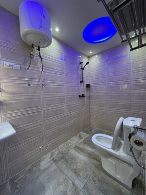 Un baño con inodoro, ducha y un calentador de pared.