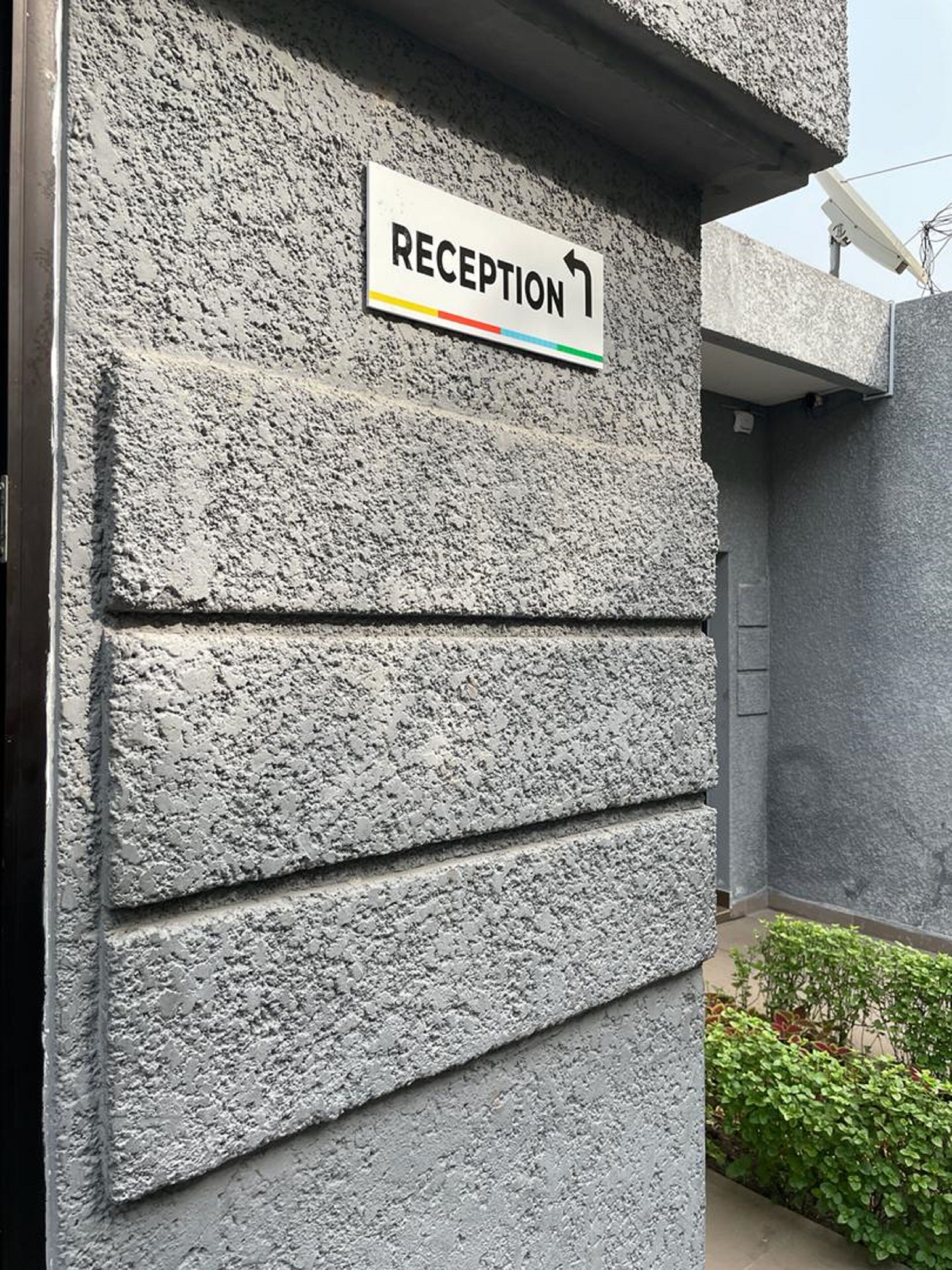 A reception sign on a textured wall, indicating the reception area.