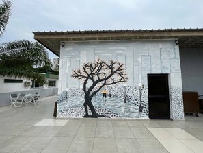 Un edificio con un mural que muestra un árbol y una persona sosteniendo un paraguas.