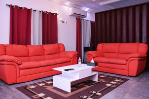 Una sala de estar con dos sofás rojos, una mesa de centro blanca y una alfombra estampada.