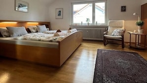 Ein Schlafzimmer mit einem Bett, einem Sessel, einem kleinen Tisch, einer Heizung und einem Fenster.