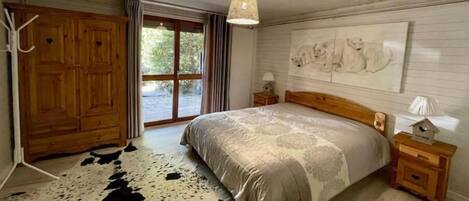 A bedroom with a large bed, wooden wardrobe, and a cowhide rug.