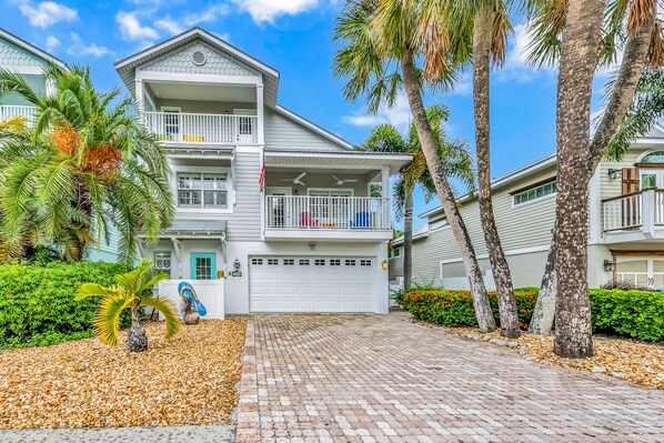 A two-story residential building with a white exterior, a garage, and a paved driveway.