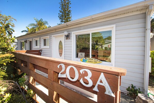 A white house with the number 203A on a wooden fence.
