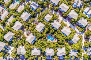 An aerial view of a residential area with uniformly shaped houses, surrounded by greenery and a central swimming pool. - Pet Friendly Home, Pool and Close to Beach! - Stones Throw (Holmes Beach)