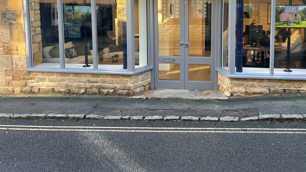 Una casa vacanze con facciata in pietra, ampie finestre e un cartello con la scritta "STAY COTSWOLD Holiday Cottages".