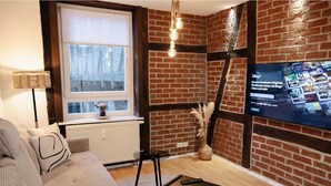 Een moderne woonkamer met een bakstenen muur, een televisie, een bank, een salontafel en een raam met uitzicht.