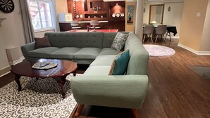 Un salon spacieux comprenant un canapé d’angle, une table basse et un coin repas avec une table et des chaises.