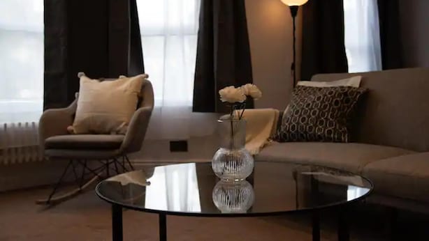 A living room with a sofa, a chair, a coffee table, and a vase with flowers. - Charming 3-bed Apartment in London (London)