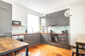 Enjoy cooking in this well-equipped kitchen with an oven, stainless steel range hood, and compact washing machine.