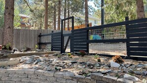 Un espacio exterior cercado, con un muro de piedra y una terraza de madera.