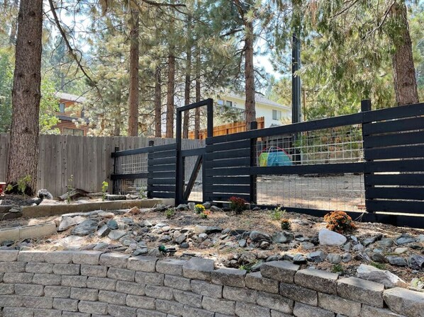 Ein von einer Mauer und einem Zaun umgebenes Außenareal mit einer Holzterrasse.