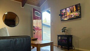 Una sala de estar con una mesa de madera, un sofá, una chimenea y un televisor montado en la pared.
