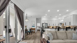 A modern kitchen with white cabinets, a central island, and a dining area with a table and chairs.