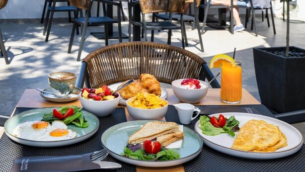 A breakfast setting with various dishes including eggs, toast, and fruit. - Hillside Elegance  (Santorini)
