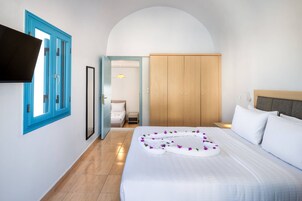 A hotel room with a bed, a wardrobe, a TV mounted on the wall, and a bathroom visible through an open door.