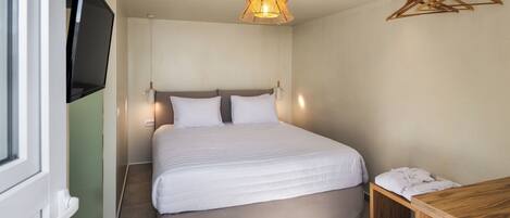 A neatly arranged bedroom with a bed, bedside table, and a hanging light fixture.