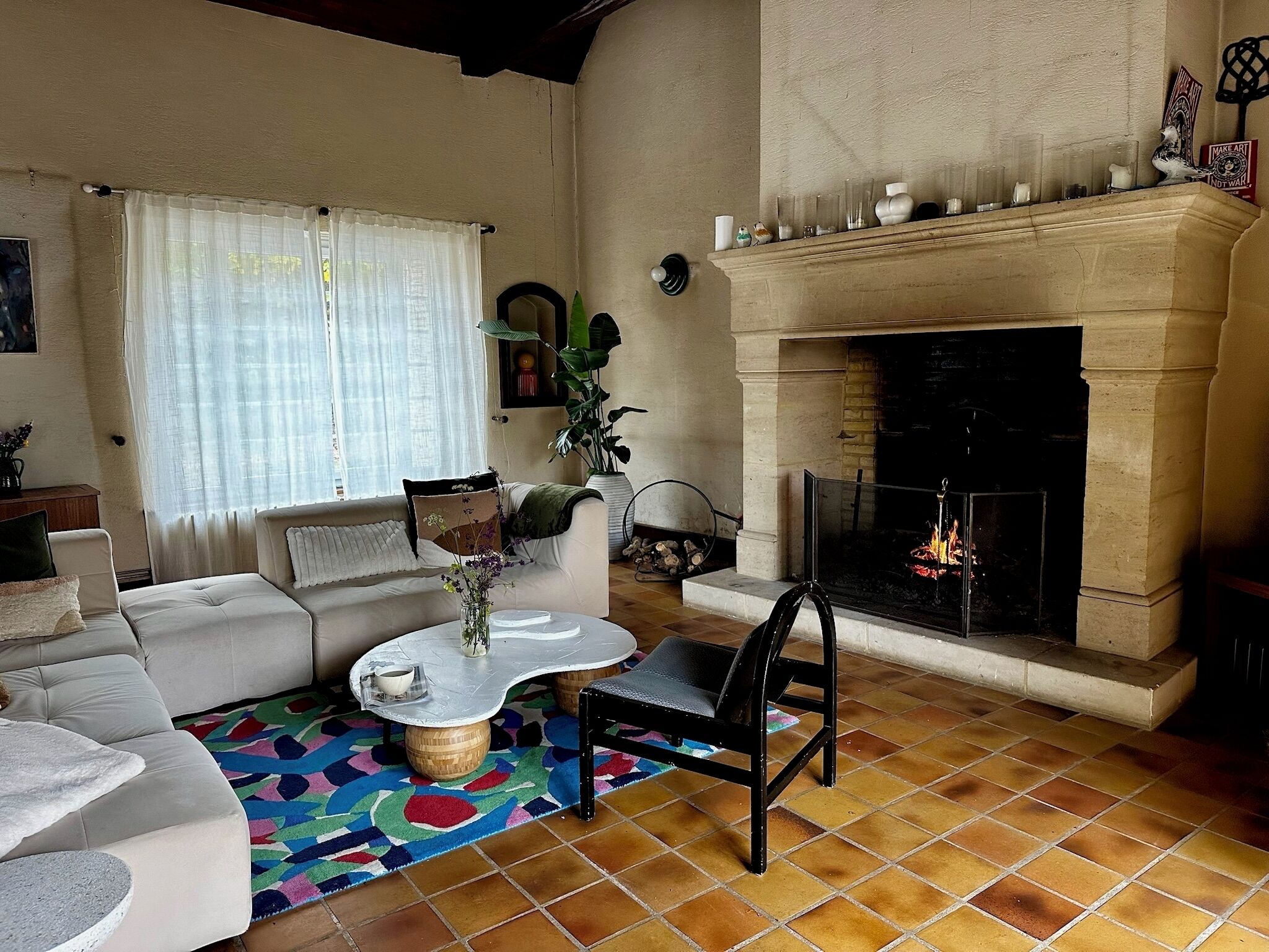 Un salon avec une cheminée, un canapé, une table basse et un tapis aux couleurs vives.