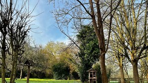 A garden with trees, a wooden structure, and yellow flowers. - Domaine Verneuil, un Havre de Paix Dans Le Perche (La Chapelle-Souëf)