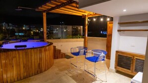 An outdoor patio area with a hot tub, two blue chairs, and a wooden pergola. - Casa Azul 1 💙 El Espinal (Cartagena de Indias)