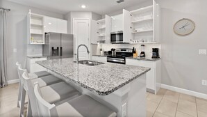 A modern kitchen with white cabinetry, granite countertops, and stainless steel appliances. - 5BR townhouse with pool near Disney area (Kissimmee)