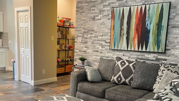 Una sala de estar con un sofá modular gris, almohadones decorativos estampados y un cuadro abstracto colorido en la pared.