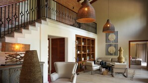 A spacious living room with a staircase, a large woven vase, a bookshelf, and a hanging pendant light. - Mountains of Hope  (Rionegro)