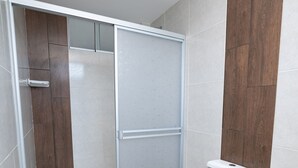 Une salle de bain avec un espace douche, des toilettes et des panneaux muraux en bois.