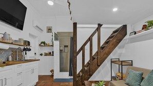 A modern kitchen with white cabinets, a wooden staircase, and a living area with a sofa and a coffee table. - 1/1 Loft Villa 2 blocks to Beach (Deerfield Beach)