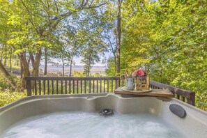 A hot tub with a wooden deck and a view of the sea.