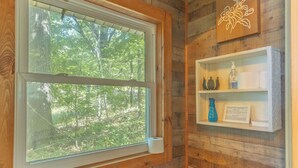 A wooden cabin bathroom with a toilet, a sink, and a window overlooking a forest. - Room on the Ridge / HOT TUB / Sleeps 2 (Wheatland)