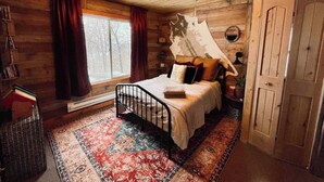 A cozy wooden bedroom with a bed, a large window, and a rustic decor. - Room on the Ridge / HOT TUB / Sleeps 2 (Wheatland)