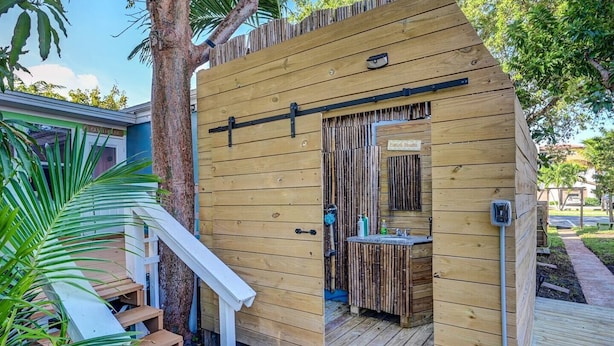 A wooden outdoor shower structure with a bamboo wall, a small sink, and a door. - Bali style 1/1 beach villa (Deerfield Beach)