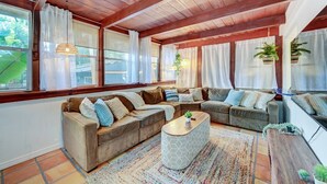 A cozy living room with wooden beams, large windows with sheer curtains, and a mix of sofas and a coffee table. - Bali style 1/1 beach villa (Deerfield Beach)