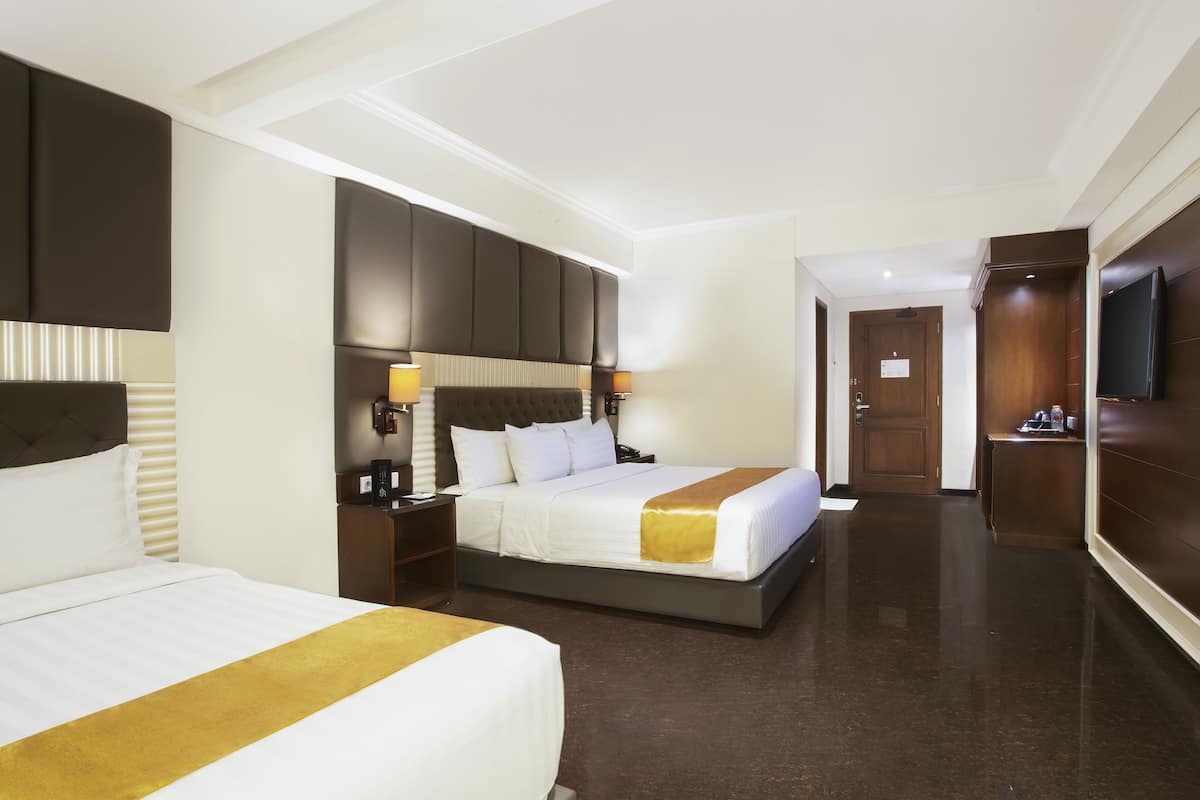 Quarto de hotel com duas camas, um espelho grande, uma televisão e um guarda-roupa de madeira.