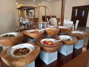 Un buffet composé de différents plats présentés dans de grands bols ronds en bois, placés sur des présentoirs.